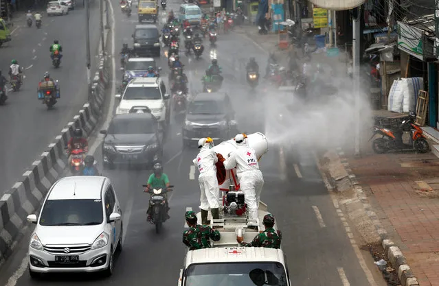 Indonesia's Red Cross personnel wearing protective suits spray disinfectant on the road to prevent the spread of the coronavirus disease (COVID-19) in Jakarta, Indonesia, March 28, 2020. (Photo by Ajeng Dinar Ulfiana/Reuters)