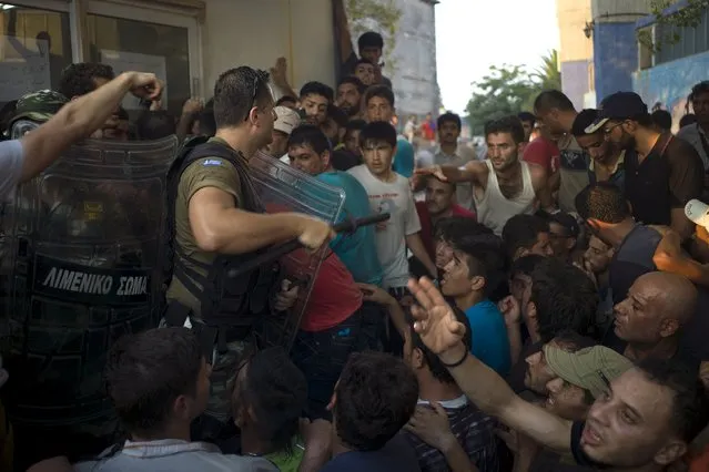 A member of the Greek coast guard special forces holds his baton as migrants crowd around during a registration procedure at the port of Mytilene on the Greek island of Lesbos, September 3, 2015. (Photo by Dimitris Michalakis/Reuters)