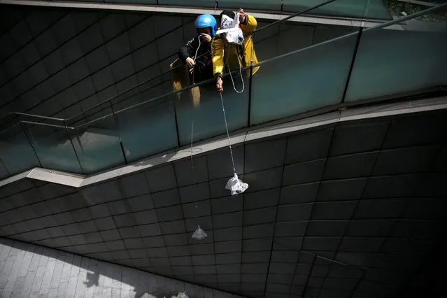 Delivery workers pull ropes to pick up food from restaurants as the nearest entrance to downstairs has been blocked following the novel coronavirus disease (COVID-19) outbreak, at the Galaxy Soho office buildings in Beijing, China on April 16, 2020. (Photo by Tingshu Wang/Reuters)