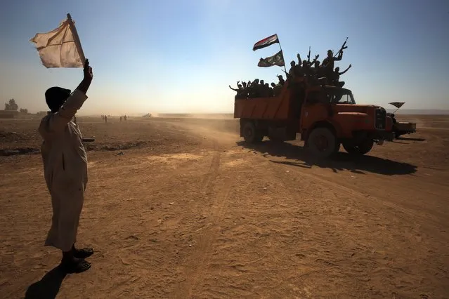 An Iraqi man, from a neighbouring village, waves a white flag as Iraqi forces and fighters from the Hashed al-Shaabi (Popular Mobilisation units) advance towards the Islamic State (IS) group's stronghold of Hawija on October 1, 2017 in their ongoing battle to recapture the town from the jihadists. (Photo by Ahmad Al-Rubaye/AFP Photo)