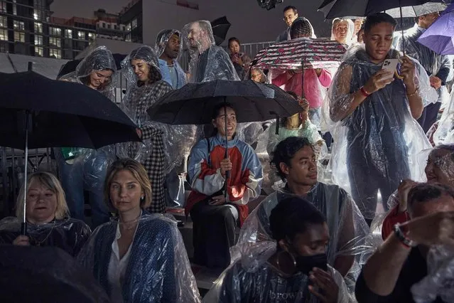 Guests wait under the rain for the Tommy Hilfiger runway show during New York Fashion Week in New York City on September 11, 2022. (Photo by Andres Kudacki/AFP Photo)