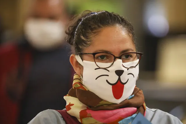 A woman wearing a face mask decorated with an animal face waits in line for a rapid coronavirus test at a train station in Buenos Aires, Argentina, Friday, April 24, 2020. (Photo by Natacha Pisarenko/AP Photo)