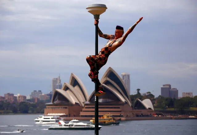 Performer Mitch Jones from Circus Oz reacts after climbing a light pole during the official launch of the annual cultural celebration The Sydney Festival, which showcases theatre, dance, circus, visual art and music during the month of January, in a park opposite the Sydney Opera House in Australia, October 25, 2017. (Photo by David Gray/Reuters)