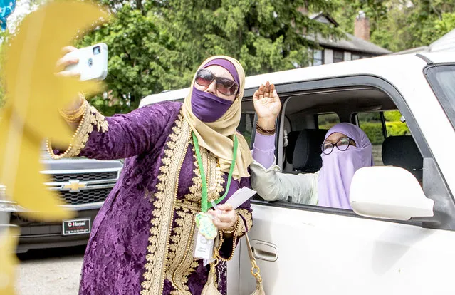 Bouchra Elharrack, of the Hill District, takes a selfie with Kashida Brackins, of Highland Park, during a drive-thru parade to celebrate Eid al-Fitr, a Muslim holiday that celebrates the end of Ramadan, Sunday, May 24, 2020, outside of the Islamic Center of Pittsburgh. (Photo by Alexandra Wimley/Post-Gazette via AP Photo)