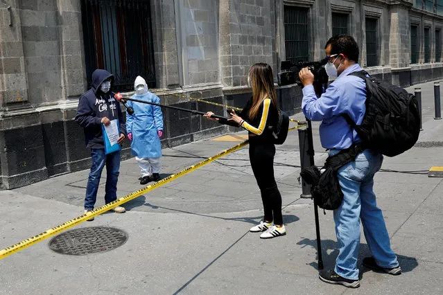 Journalists interview a man, who says he is infected with the coronavirus disease (COVID-19), while he holds a protest outside the National Palace to demand  the reconnection of electricity at his house in Mexico City, Mexico on May 28, 2020. (Photo by Carlos Jasso/Reuters)