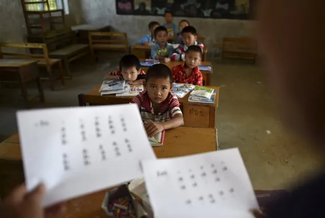 Students look at their teacher holding papers of the new curriculum at a classroom of Dalu primary school in Gucheng township of Hefei, Anhui province, China, September 8, 2015. The school, opened in 2006 and has never acquired a legal license, may face a shutdown order from the government. There are currently over 160 students in the school, mostly “leftover children”, whose parents left their hometown to earn a living, local media reported. (Photo by Reuters/Stringer)
