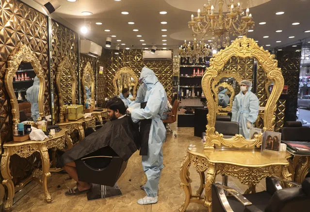 A hairdresser in personal protective suit attends to a customer at a hair salon in New Delhi, India, Friday, June 5, 2020. Businesses and shops reopened in many states as a three-phase plan to lift the nationwide coronavirus lockdown began despite an upward trend in new infections. Indian Prime Minister Narendra Modi’s government has stressed that restrictions are being eased to focus on promoting economic activity, which has been severely hit by the lockdown. (Photo by Manish Swarup/AP Photo)