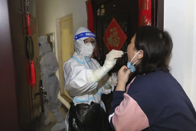 A medical worker takes swab sample from a residents during a door-to-door Covid-19 screening in Zhengzhou in central China's Henan province Tuesday, November 1, 2022. Access to an industrial zone in the central Chinese city of Zhengzhou was suspended Wednesday after the city reported 64 coronavirus cases and workers who assemble Apple Inc. iPhones left their factory in the zone following outbreaks. (Photo by Chinatopix via AP Photo)