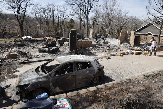 Andrine Shufran, right, looks through the ashes that are left of her home in the Hidden Oaks neighborhood in Stillwater, Okla., Monday, March 17, 2025, after wildfires burned through the area Friday. (Photo by Alonzo Adams/AP Photo)