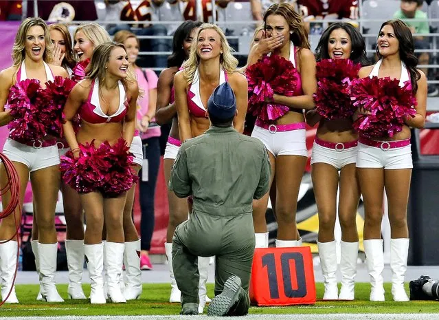 Arizona Cardinals cheerleader Claire Thorton, center, smiles as Air Force Capt. Eric Straub proposes to her during the first half of an NFL football game against the Washington Redskins, Sunday, October 12, 2014, in Glendale, Ariz. Thorton accepted the proposal. (Photo by Rick Scuteri/AP Photo)