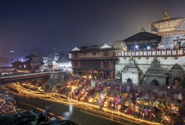 Nepalese devotees release oil lamps in memory of deceased family members as they observe the Balachaturdashi festival at Pashupati temple in Kathmandu, Nepal, 22 November 2022. Thousands of people from all over the country have gathered at the Pasupati temple to light the oil lamps at the Bagmati river in the name of their departed beloved ones during the year. The following morning family members will spread Satabij, seven kinds of seeds-paddy, barley, sesame, wheat, gram, maize and finger millet, around the temple premises. Seeds are sown with the belief that the departed souls receive salvation. (Photo by Narendra Shrestha/EPA/EFE)