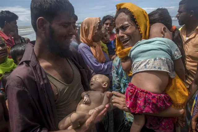 Naseer Ud Din, a Rohingya Muslim man, holds his infant son, Abdul Masood, who drowned when the boat they were traveling in capsized just before reaching the shore, as his wife, Hanida Begum, cries upon reaching the Bay of Bengal shore in Shah Porir Dwip, Bangladesh, on September 14, 2017. (Photo by Dar Yasin/AP Photo)