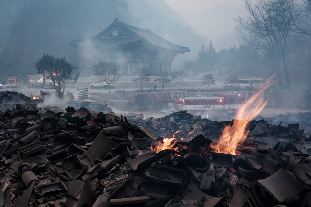 Embers remain among the debris after most of the buildings were burned to the ground in a wildfire at Gounsa Temple in Uiseong on March 26, 2025. At least 18 people have been killed in one of South Korea's worst wildfire outbreaks, with multiple blazes burning and causing “unprecedented damage”, the acting president said. (Photo by Yasuyoshi Chiba/AFP Photo)