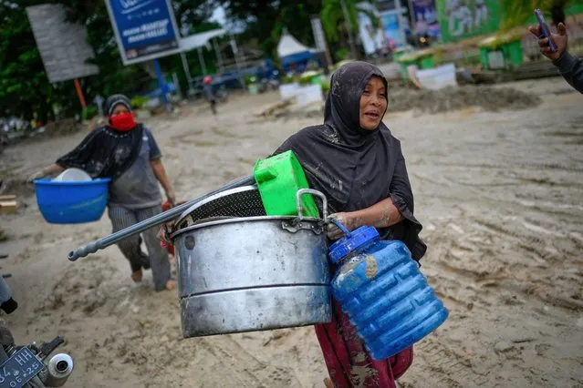 Villagers carry their belongings from their homes to evacuation camps following flash floods in North Luwu regency in Indonesia's South Sulawesi on July 15, 2020, a day after three rivers overflowed due to torrential rains. At least 15 people were killed and dozens missing after flash floods left hundreds of houses buried in mud on the Indonesian island of Sulawesi, authorities said on July 14. (Photo by Hariandi Hafid/AFP Photo)