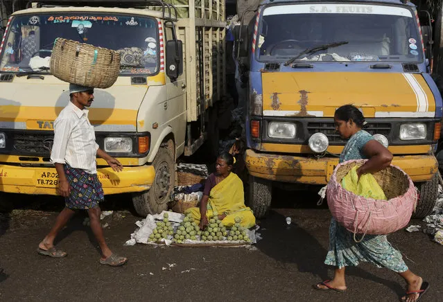 An Indian roadside vendor sits between trucks to sell fruits at a wholesale market in  Bangalore, India, Tuesday, September 29, 2015. India's central bank on Tuesday cut its key interest rate by half a percentage point, aiming to spur economic growth as inflation cooled to the lowest since November. (Photo by Aijaz Rahi/AP Photo)