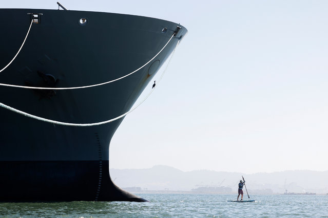 A paddleboarder passes a ship in the waters off Crane Cove Park in San Francisco, US on May 20, 2025. (Photo by Jessica Christian/San Francisco Chronicle via AP Photo)