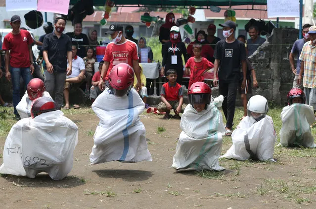 Children participate in a sack racing competition using helmets as face shields in anticipation of the spread of the novel coronavirus (COVID-19) pandemic during celebration of Indonesia's 75th Independence Day in Deli Serdang, North Sumatra, Indonesia on August 17, 2020. Various activities are held while still applying health protocols to curb the spread coronavirus. (Photo by Kiki Cahyadi/Anadolu Agency via Getty Images)