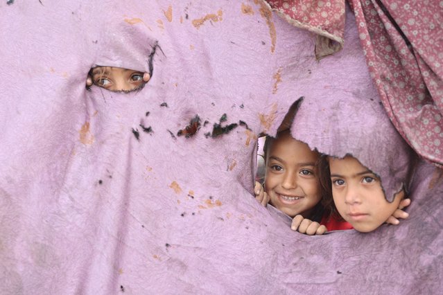 Palestinian children peek out of holes in their tent at a makeshift displacement camp set up amid building rubble in Gaza City on May 12, 2025. Israeli Prime Minister Benjamin Netanyahu said on May 12 that the release of a US-Israeli hostage announced by Hamas would not lead to a ceasefire in the Gaza Strip or the release of Palestinian detainees. (Photo by OMar Al-Qattaa/AFP Photo)