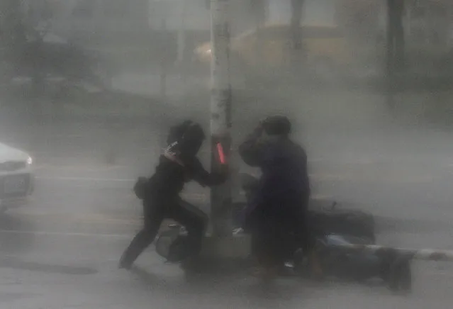 A rescuer tries to assist a motorist victim as high winds and rain of Super Typhoon Meranti lash Kaohsiung, southern Taiwan, 14 September 2016. (Photo by Ritchie B. Tongo/EPA)