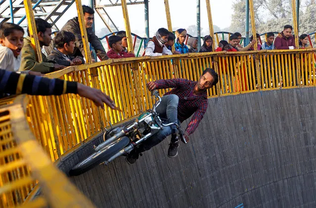 A stunt performer rides a motorcycle on the walls of the “Well of Death” at the Magh Mela fair in Allahabad, India January 17, 2018. (Photo by Jitendra Prakash/Reuters)
