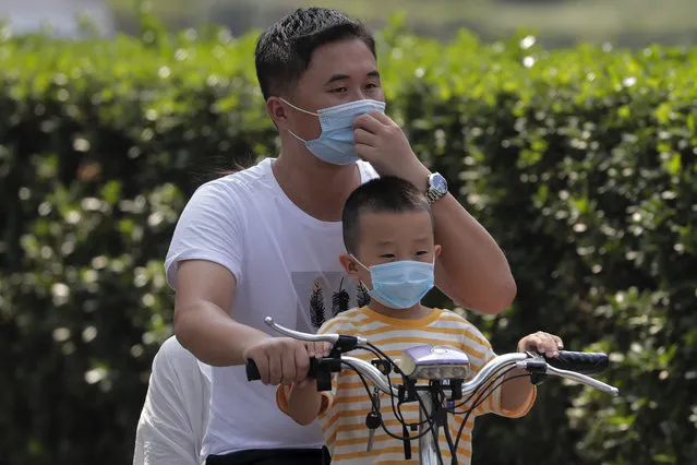A man and a child wearing face masks to help curb the spread of the coronavirus ride on an electric-powered scooter past the Xinfadi wholesale food market district in Beijing, Sunday, September 6, 2020. According to local news report, Xinfadi market, the capital's biggest wholesale food market have reopen for wholesale operation after it was shutdown following the coronavirus outbreak. China's government on Sunday reported several new coronavirus infections, all believed to have been acquired abroad, and no deaths. (Photo by Andy Wong/AP Photo)