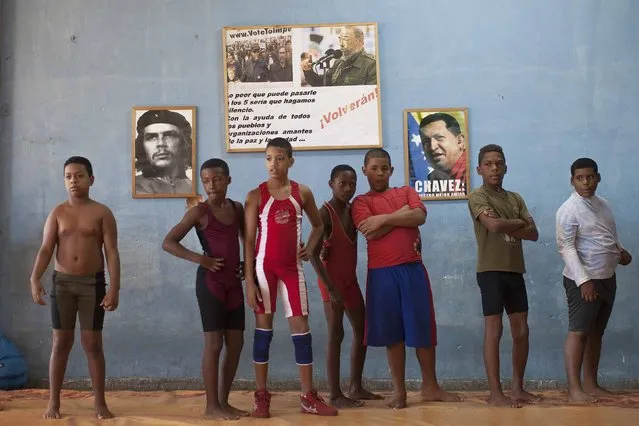 Children make a line during a wrestling training session in front of pictures of late Cuban revolutionary hero Ernesto “Che” Guevara (L),  former Cuban President Fidel Castro (C) and Venezuela's late President Hugo Chavez, on the outskirts of Havana, November 1, 2014. (Photo by Alexandre Meneghini/Reuters)