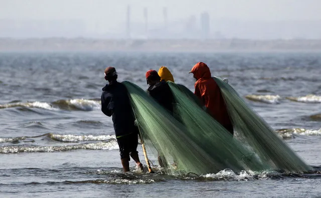 Fishermen carry a net as they catch small fish at the Arabian sea in Karachi, Pakistan, 06 February 2018. (Photo by Rehan Khan/EPA/EFE)