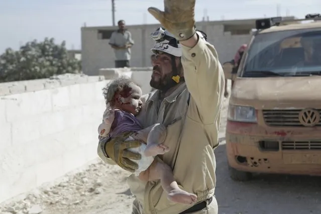 A civil defence member carries an injured baby that survived from under debris at a site hit by what activists said was an airstrike by forces loyal to Syria's President Bashar al-Assad, in the town of Marshamsha, in the southern countryside of Idlib, Syria October 20, 2015. (Photo by Khalil Ashawi/Reuters)