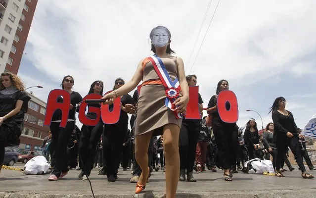 A teacher wearing a mask of Chilean President Michelle Bachelet takes part in a rally against the government to demand an increase in their salaries in Valparaiso city, northwest of Santigo November 27, 2014. The word reads, “Burden”. (Photo by Rodrigo Garrido/Reuters)