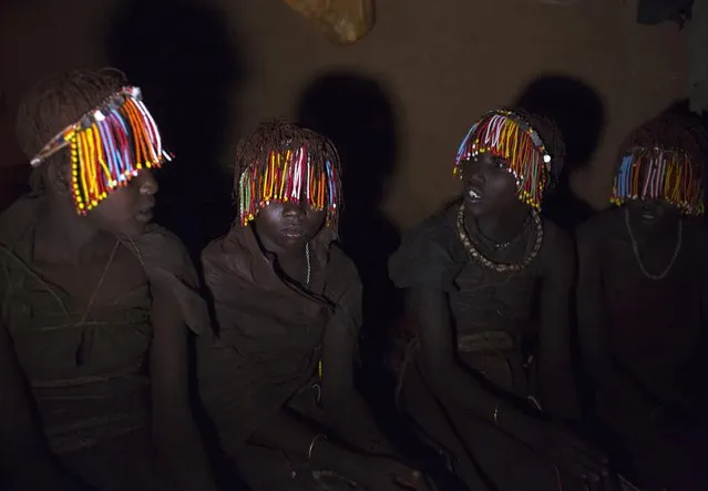 Pokot girls wearing beads and animal skins sit in a secluded hut slightly more than one week prior to an initiation ceremony marking their passing over into womanhood, about 80 km (50 miles) from the town of Marigat in Baringo County November 24, 2014. They are part of a group of over a hundred girls that will take part in the ceremony lasting one night and through the next day. Before the ceremony, as Pokot tradition dictates, the girls are secluded for over a month, out of sight of the men in the community. (Photo by Siegfried Modola/Reuters)
