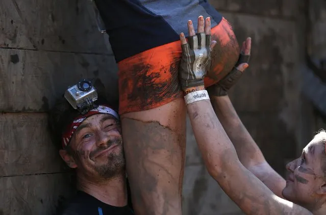 Participants climb over a wall at the “Tough Mudder” endurance event series in Arnsberg in this September 6, 2014 file photo. (Photo by Ina Fassbender/Reuters)