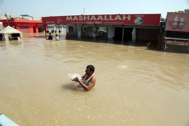 A man wades through a flooded area as people affected by the floods receive relief supplies, in Multan district, Punjab province, Pakistan, 15 September 2025. The IMF is expected to assess Pakistan's flood-related financial needs later this month, as the country is reeling from months of monsoon rains that have killed hundreds, displaced over 2 millions, and damaged homes, crops and infrastructure since late June 2025. (Photo by Mansoor Abbas/EPA)