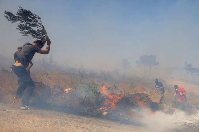 A firefighter and local residents work to extinguish a wildfire burning in Keratea, near Athens, Greece, on June 30, 2024. (Photo by Giorgos Moutafis/Reuters)