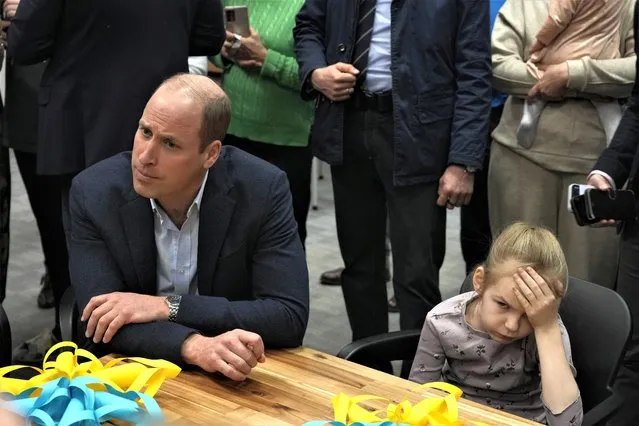 Young girl holds her head as Britain's Prince William visits an accommodation centre, for Ukrainians who fled the war, in Warsaw, Poland, Wednesday, March 22, 2023. Photo by Czarek Sokolowsk/AP Photoi)