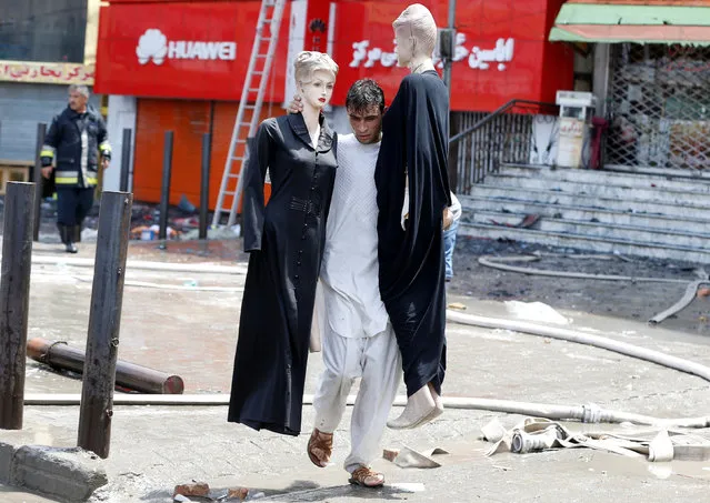 An Afghan shopkeeper carries mannequins after a fire broke out a shopping mall in Kabul, Afghanistan August 4, 2016. (Photo by Omar Sobhani/Reuters)