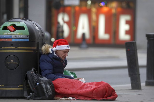 A homeless man wears a santa hat as he sits on Oxford Street in London, Saturday, December 26, 2020. (Photo by Kirsty Wigglesworth/AP Photo)