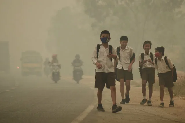 Students walk along a street as they are released from school to return home earlier due to the haze in Jambi, Indonesia's Jambi province, September 29, 2015. (Photo by Wahdi Setiawan/Reuters/Antara Foto)