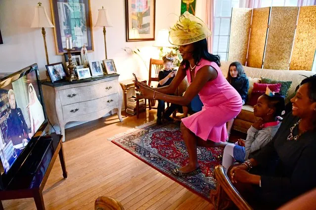 Jenice Armstrong of Burlington, N.J. takes a photo during a television viewing party of the royal wedding of Meghan Markle and Prince Harry , Saturday, May 18, 2018, at the Armstrong-Turner residence in Burlington, N.J. From pubgoers in pajamas to merrymakers in finery at a posh hotel, Americans cheered and teared up Saturday as they watched Meghan Markle marry Prince Harry in a royal wedding with trans-Atlantic resonance. (Photo by Corey Perrine/AP Photo)