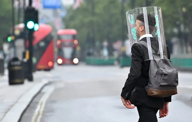 A pedestrian wearing a form of PPE (personal protective equipment) of a perspex full-face covering, as a precautionary measure against COVID-19, walks across Oxford Street in central London on June 11, 2020, as non-essential shops prepare to re-open on June 15. Britain's current guidelines on social distancing remain at two metres (2M), but business leaders and some politicians are on Thursday calling for it to be reduced to one (1M), or one-and-a-half (1.5M) metres. (Photo by Justin Tallis/AFP Photo)