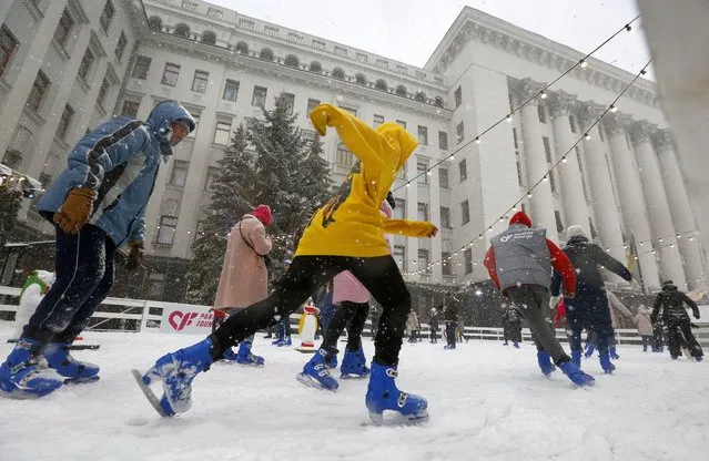 People skate under heavy snow at the ice rink set up outside the Ukrainian President office in Kyiv, Ukraine, Wednesday, December 23, 2020. Despite of COVID-19 quarantine restrictions, a lot of Ukrainians are still attending outdoor Christmas events, often ignoring protective measures. (Photo by Efrem Lukatsky/AP Photo)