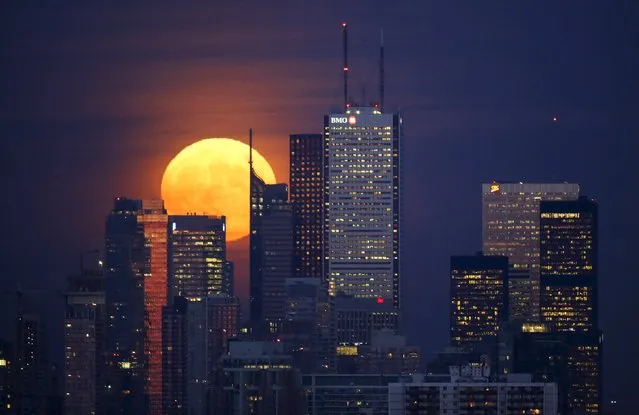 The moon rises behind the skyline and financial district in Toronto, Canada, November 25, 2015. (Photo by Mark Blinch/Reuters)