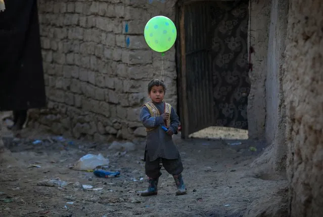 An Afghan internally displaced boy poses for a photograph as he holds a balloon near to a temporary shelter at an Internally Displaced Persons (IDPs) camp on the outskirts of Kabul, Afghanistan on 19 January 2021. Over 18.4 million Afghans including 9.7 million children in Afghanistan desperately need life-saving support, said Save the Children in a statement on 19 January, therefore the NGO is calling for billions of dollars in aid to cope with the challenges. The NGO says a combination of conflict, poverty, and the Coronavirus pandemic continue to have devastating impacts on the population and continue to fuel humanitarian needs in Afghanistan. (Photo by Hedayatullah Amid/EPA/EFE)