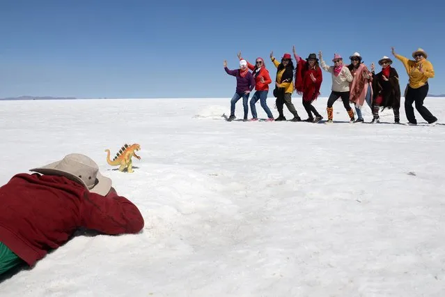 A boy takes photos of tourists behind a toy dinosaur for a fee, at the Uyuni Salt Flat in Bolivia on March 27, 2022. (Photo by Claudia Morales/Reuters)