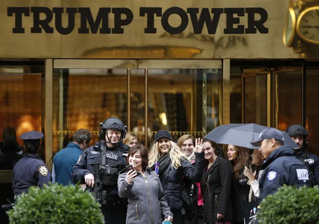 In this November 15, 2016 file photo, a passersby stops for a selfie with a heavily-armed New York City police officer at the main, Fifth Avenue entrance to Trump Tower in New York. Outside Donald Trump's gilded skyscraper, many in the slow-moving sidewalk throng come for the sole purpose of snapping selfies, some to capture a bit of history and others to offer the new president their one-fingered salute. (Photo by Kathy Willens/AP Photo)