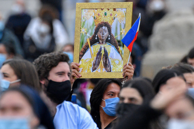 A Philippine attendee holds a picture of Our Lady of the Philippines, and the Philippine flag during the Pope's weekly Angelus prayer on March 14, 2021 at St. Peter's Square in The Vatican. (Photo by Tiziana Fabi/AFP Photo)