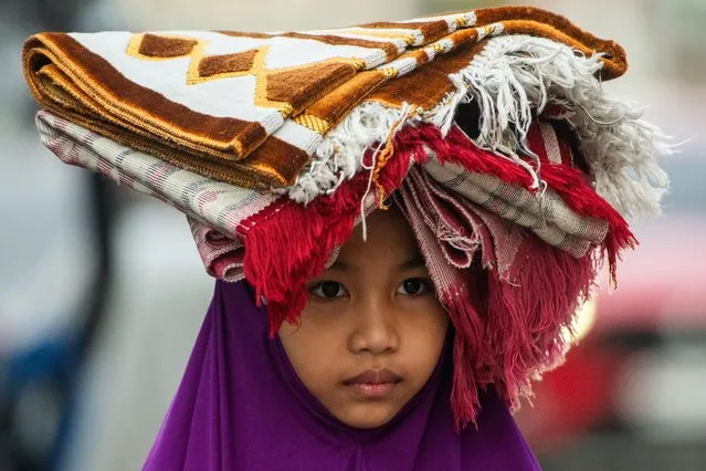 A girl carries prayer rugs on her way to a mosque for Eid al-Adha prayers in Marikina City, Metro Manila, Philippines on June 28, 2023. (Photo by Lisa Marie David/Reuters)