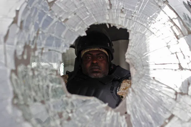 A police officer drives a police truck with its windshield smashed during a protest by supporters of presidential candidate Maryse Narcisse in Port-au-Prince, Haiti, Monday, November 21, 2016. Supporters of the Lavalas Family candidate marched either claiming victory for Narcisse or claiming electoral fraud that would keep her from office.  Election results are expected no earlier than Sunday, No. 27. (Photo by Ricardo Arduengo/AP Photo)