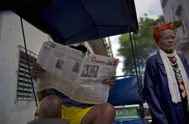 In this February 3, 2015 file photo, a man reads a copy of the official newspaper of the Central Committee of the Cuban Communist Party, Granma, as a woman walks past, in old Havana. Cuba is slightly loosening controls on its state-run media under its new president. (Photo by Ramon Espinosa/AP Photo)