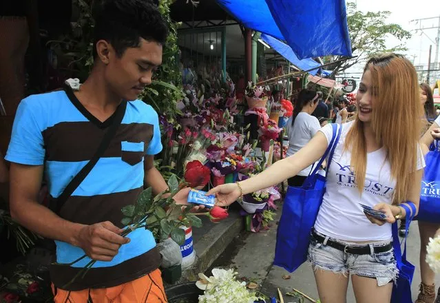 A man receives a pack of condoms from a saleslady, as part of a promotional gimmick, on the eve of Valentine's Day in Manila, February 13, 2015. (Photo by Romeo Ranoco/Reuters)