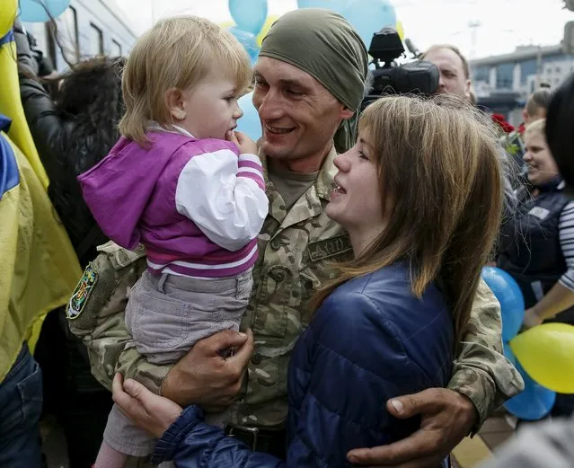 A Ukrainian serviceman embraces his wife and child after returning from the frontline in the eastern regions, at a railway station in Kiev, Ukraine, September 9, 2015. (Photo by Gleb Garanich/Reuters)